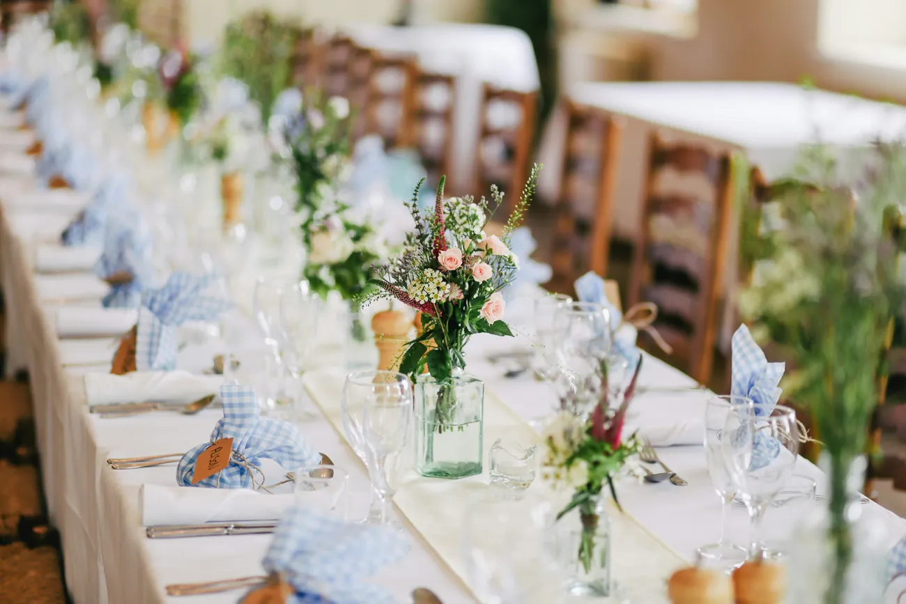 A wedding reception table laid with flowers and glassware
